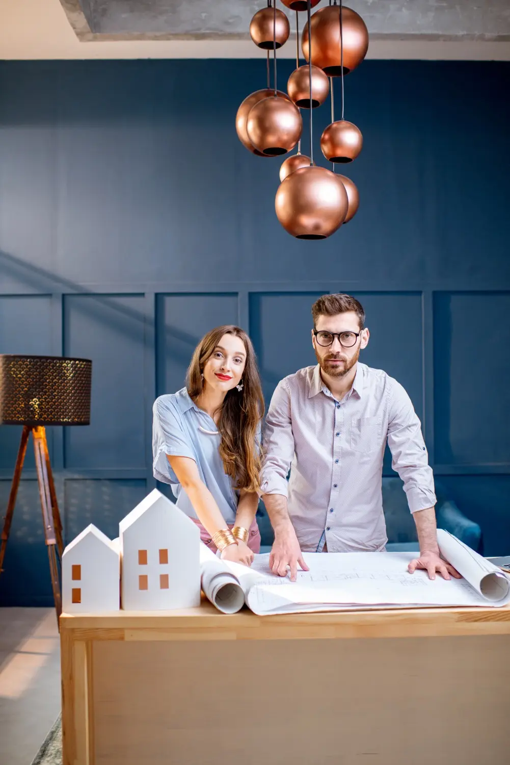 Architecte d’intérieur accompagnant un couple dans la conception d’un projet de rénovation avec plans et maquette de maison