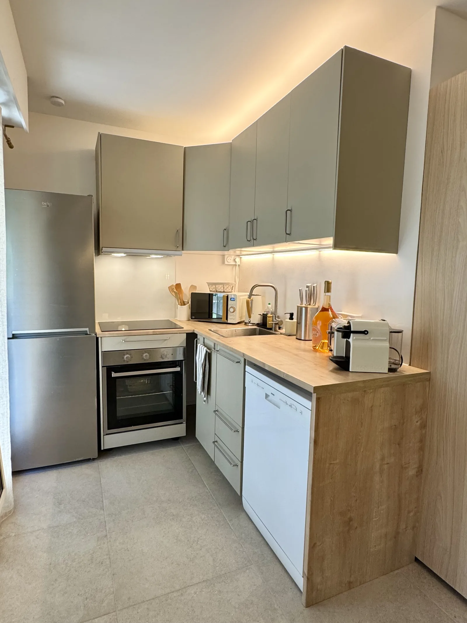 Photo réelle de la cuisine installée dans un studio rénové à Nice Cimiez, façades grises et plan de travail bois