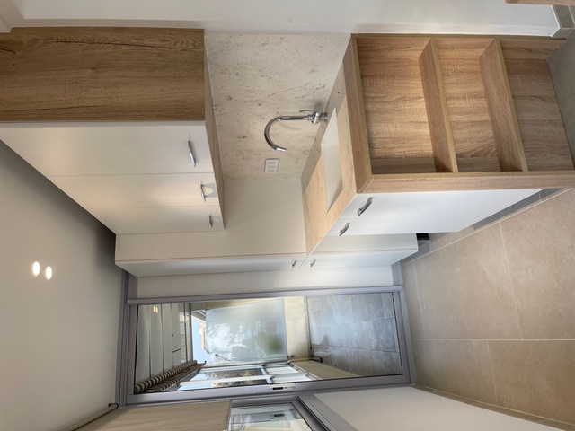 Vue d’une cuisine contemporaine avec étagères en chêne sur mesure et façades blanches design