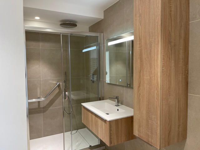 Vue d’une salle de bain contemporaine avec douche à l’italienne et meuble suspendu en chêne