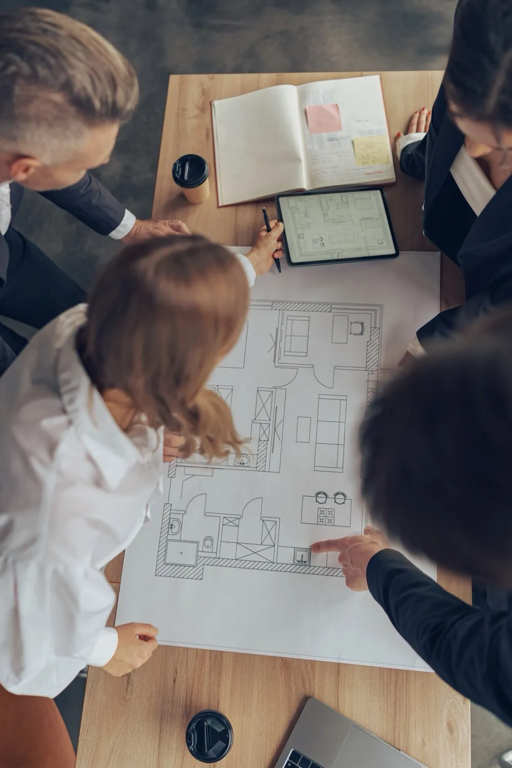 Réunion de travail autour d’un plan d’appartement pour étudier l’aménagement et la rénovation intérieure d’un logement