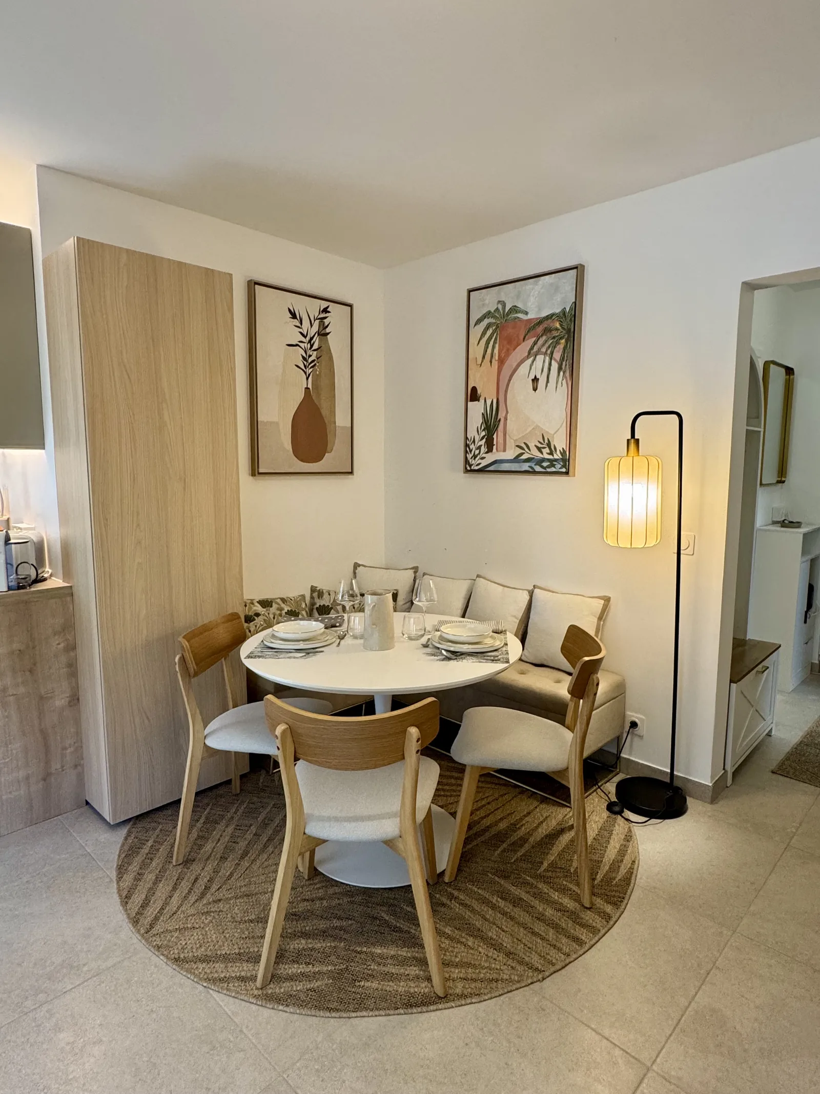 Photo réelle du coin repas installé dans un studio rénové à Nice Cimiez, table ronde et banquette avec coussins