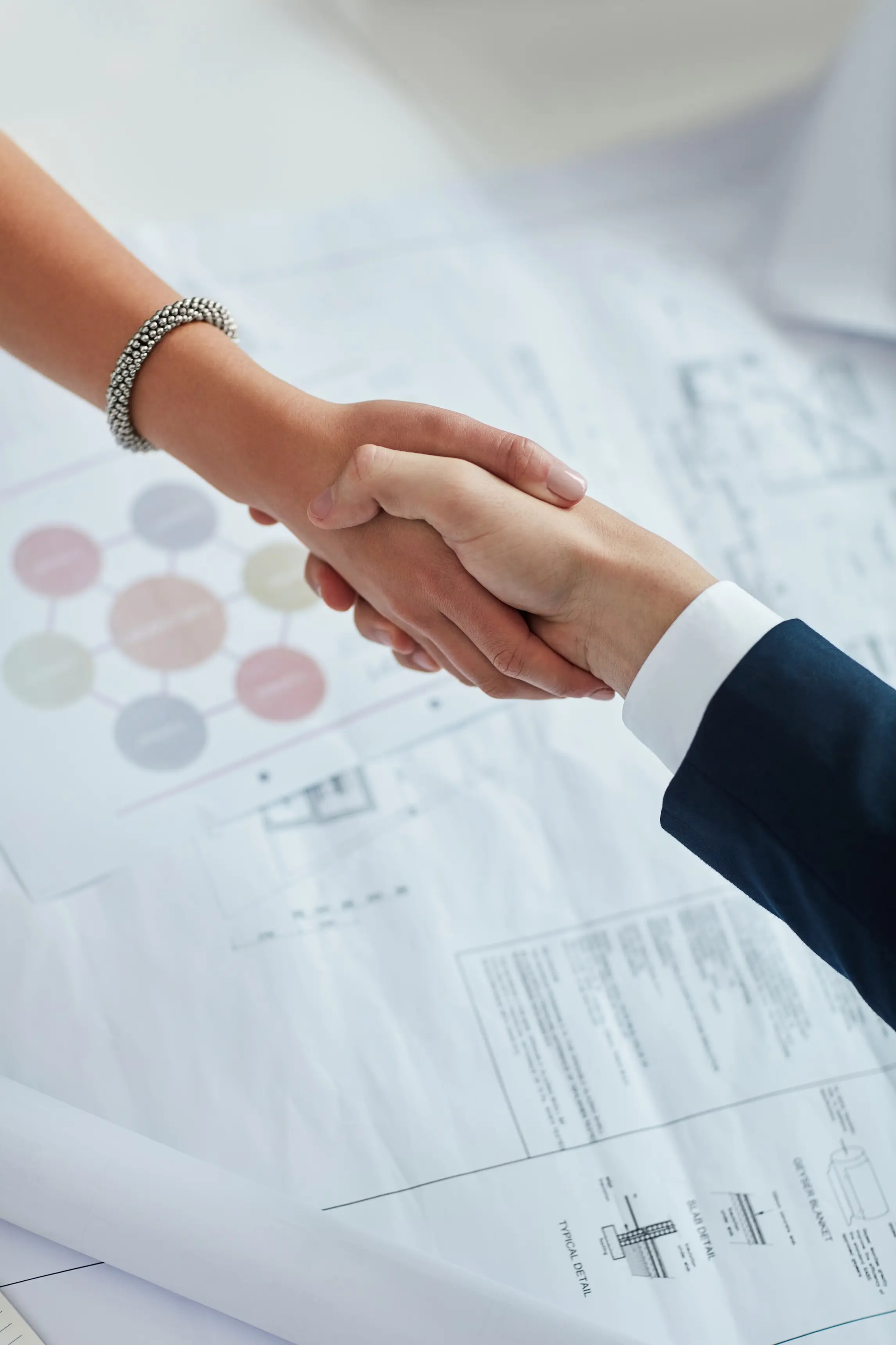 Poignée de main entre client et architecte pour la signature d’un projet de rénovation intérieure sur plan architectural